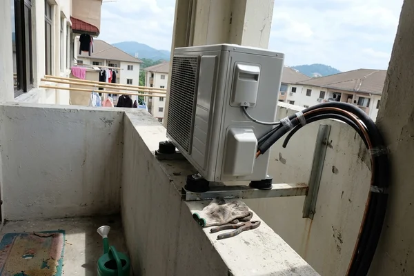 New outdoor unit on an L-bracket with vibration pads on a condo ledge
