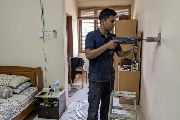 Technician drilling the wall hole for aircon piping