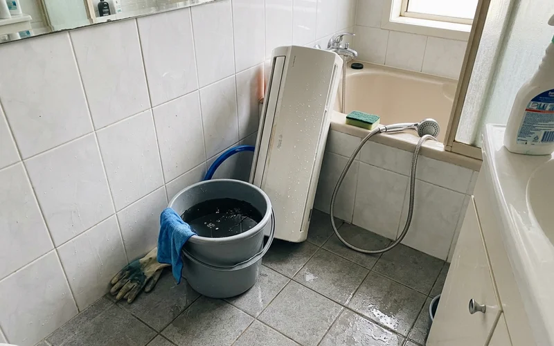 Bucket of murky rinse water beside a just-washed indoor unit