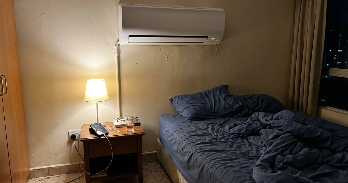 Indoor aircon with an orange timer light blinking in a dim bedroom