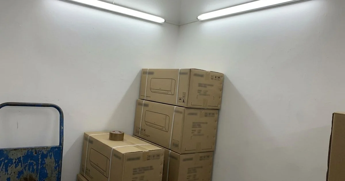 Boxed aircon units stacked in a small electrical shop storeroom