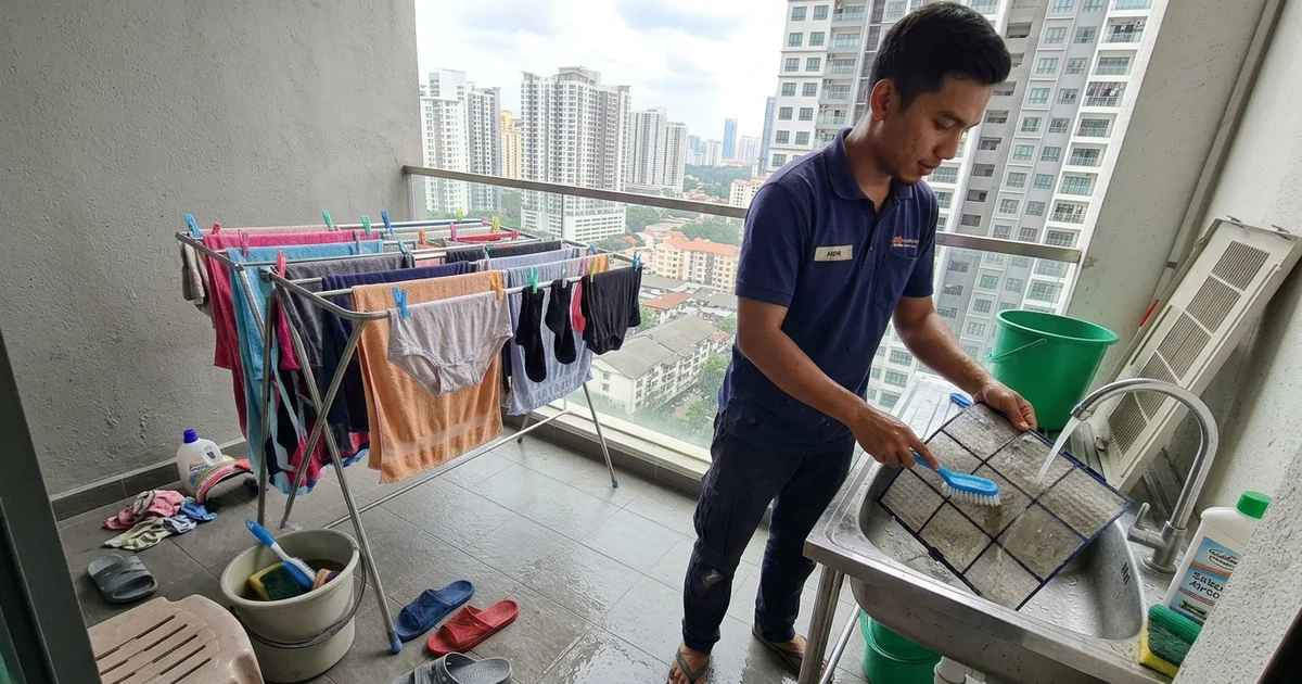 Technician rinsing aircon filters at a condo balcony sink in Kuala Lumpur